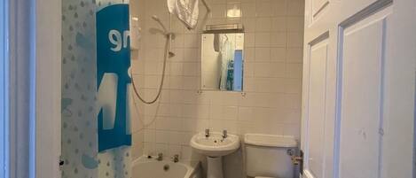 Un baño pequeño y estrecho con bañera, lavabo e inodoro.