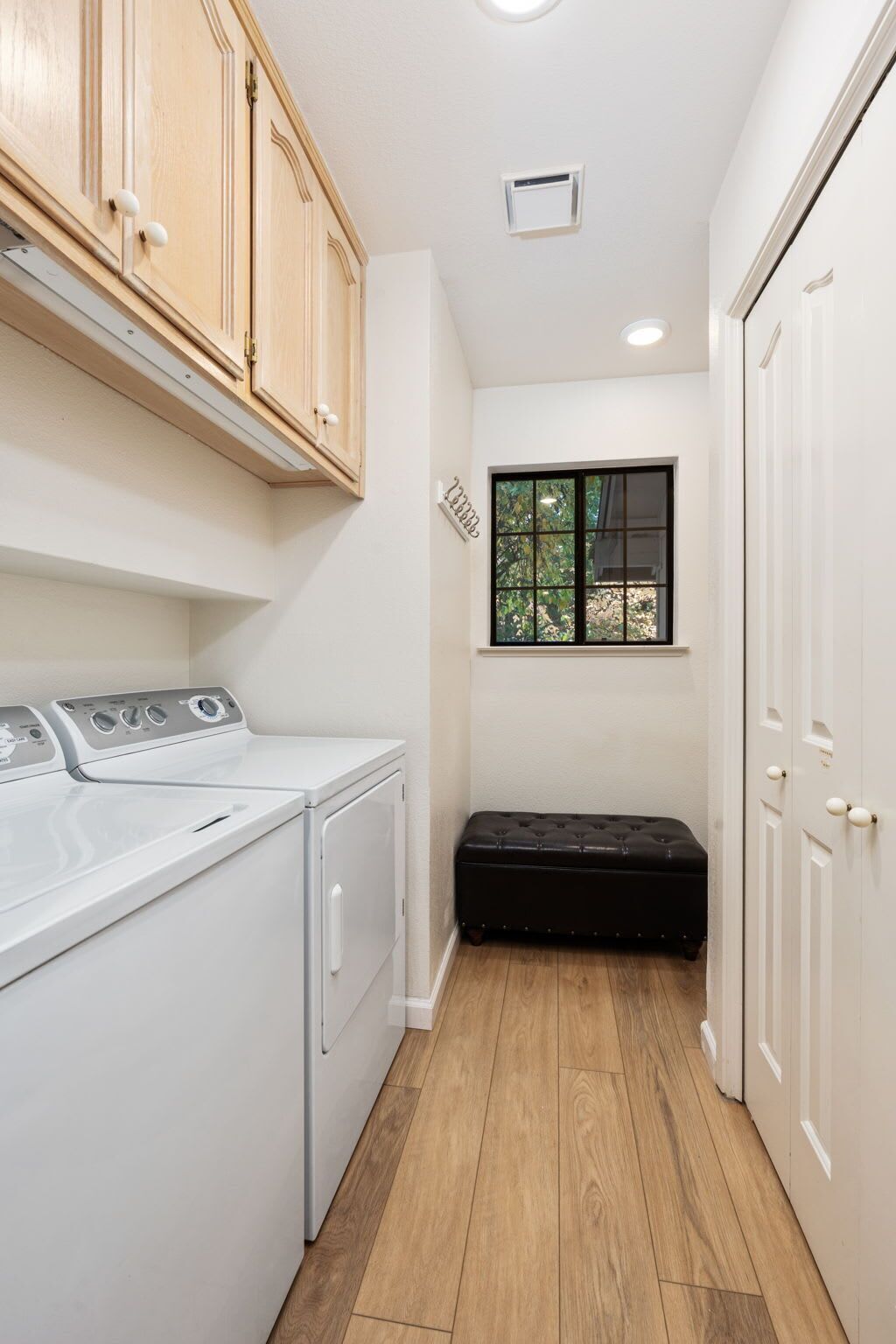 A laundry room with a washing machine, a dryer, and a bench.