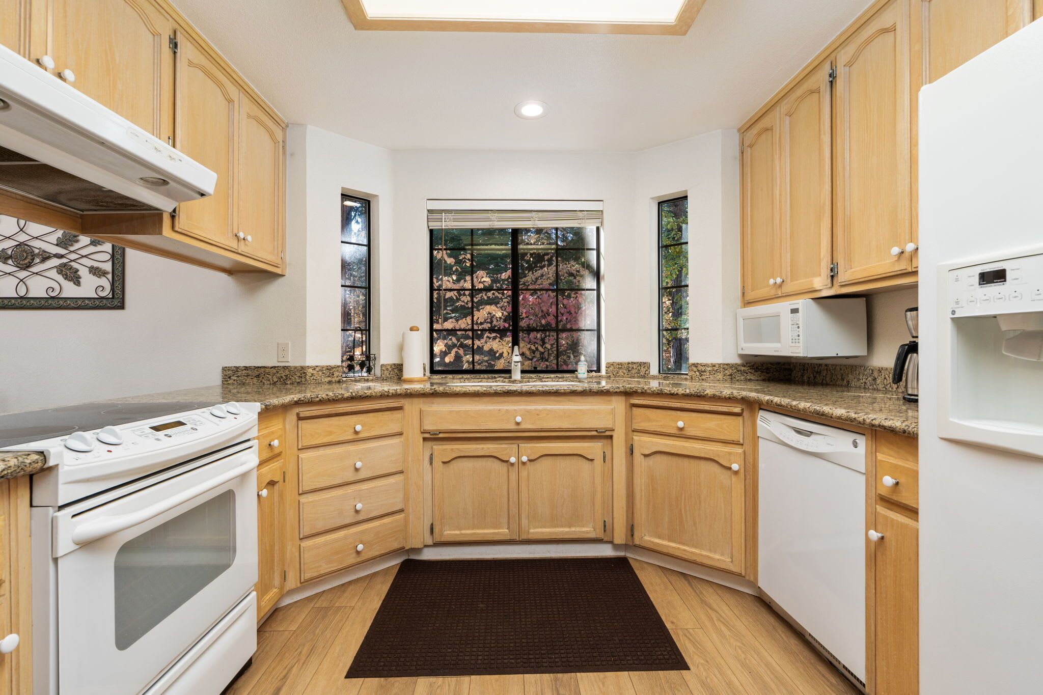 A modern kitchen with wooden cabinets, a built-in oven, microwave, and dishwasher.