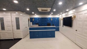 A reception area with a blue counter, white lockers, and a ceiling with recessed lighting. - KRISHNA SAI SUITES (Rahata)