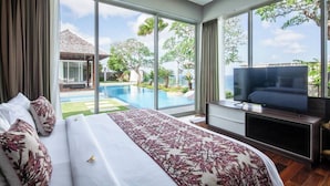 A bedroom with a large bed, a TV, and a view of a swimming pool and outdoor area.
