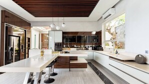 A modern kitchen with a central island, pendant lighting, and a view of the outdoors.