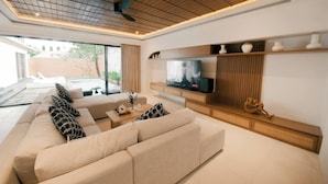 A modern living room with a large beige sofa, a flat-screen TV, and a wooden entertainment unit. - SALE40% Seminyak Villa 3BR around ShiShi Nightclub (Seminyak)