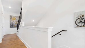 A staircase with white walls and a wooden floor, leading to an upper level. - G St Loft, Downtown Bentonville (Bentonville)