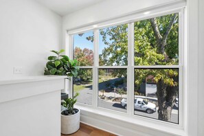 A room with a large window, white walls, and a potted plant. - G St Loft, Downtown Bentonville (Bentonville)