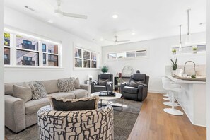 A modern living room with a sofa, armchairs, a coffee table, and a bar area with stools. - G St Loft, Downtown Bentonville (Bentonville)