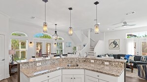 A spacious kitchen with granite countertops, white cabinetry, and pendant lighting. - Destiny In Emerald Green 3 Bedroom Home (Destin)