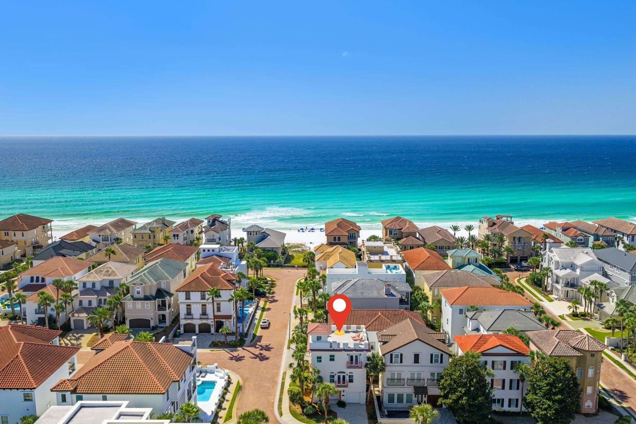 Ein Küstenwohngebiet mit Häusern, blauem Himmel und dem Meer im Hintergrund.
