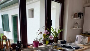 Una cocina con un amplio ventanal, armarios blancos y una encimera con diversos objetos.