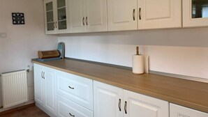Una cocina con armarios blancos, encimera de madera y un rollo de papel de cocina.