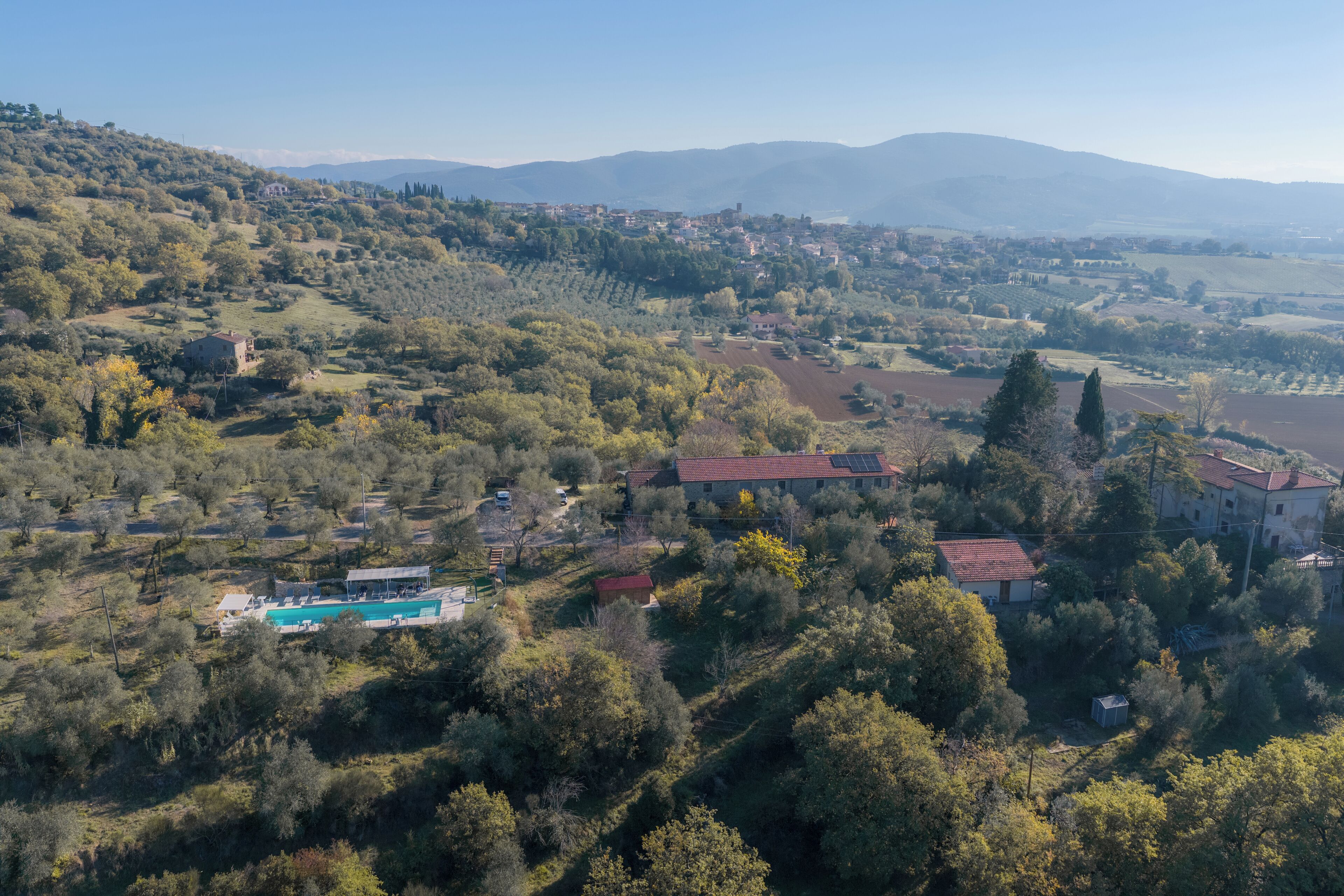 A rural landscape with a large house surrounded by trees and fields.