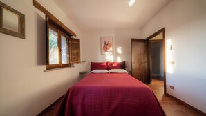 A bedroom with a large bed, a window, a door, and a wall-mounted light fixture. - Farmhouse Il Mulino delle canutole - Il Granaio (Magione)