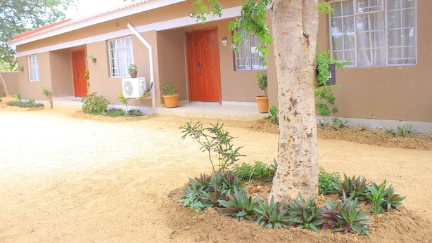 A two-story building with a red door, windows, and potted plants. - Blue Ridge Escape Guest House (Kasane)