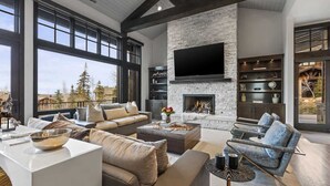 A spacious living room with a fireplace, large windows, and modern furniture. - Abode on Ruby Run, ski-in/ski-out, hot tub, sauna, fire pit (Park City)
