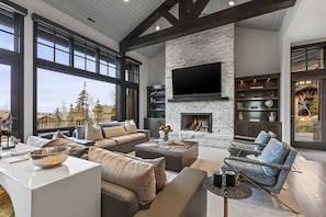 A spacious living room with a fireplace, large windows, and modern furniture. - Abode on Ruby Run, ski-in/ski-out, hot tub, sauna, fire pit (Park City)