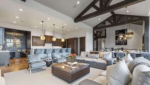A spacious living area with a modern kitchen, dining area, and a large sofa set. - Abode on Ruby Run, ski-in/ski-out, hot tub, sauna, fire pit (Park City)
