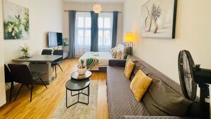 Ein moderner, gut beleuchteter Raum mit Essbereich, einer Couch und einem Fernseher.