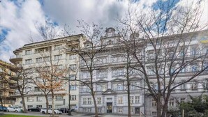 Ein mehrstöckiges Gebäude im klassischen Stil, mit einem zentralen Eingang und symmetrisch angeordneten Fenstern.