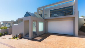 Een modern herenhuis met garage, balkon en een klein buitenstuk met planten.