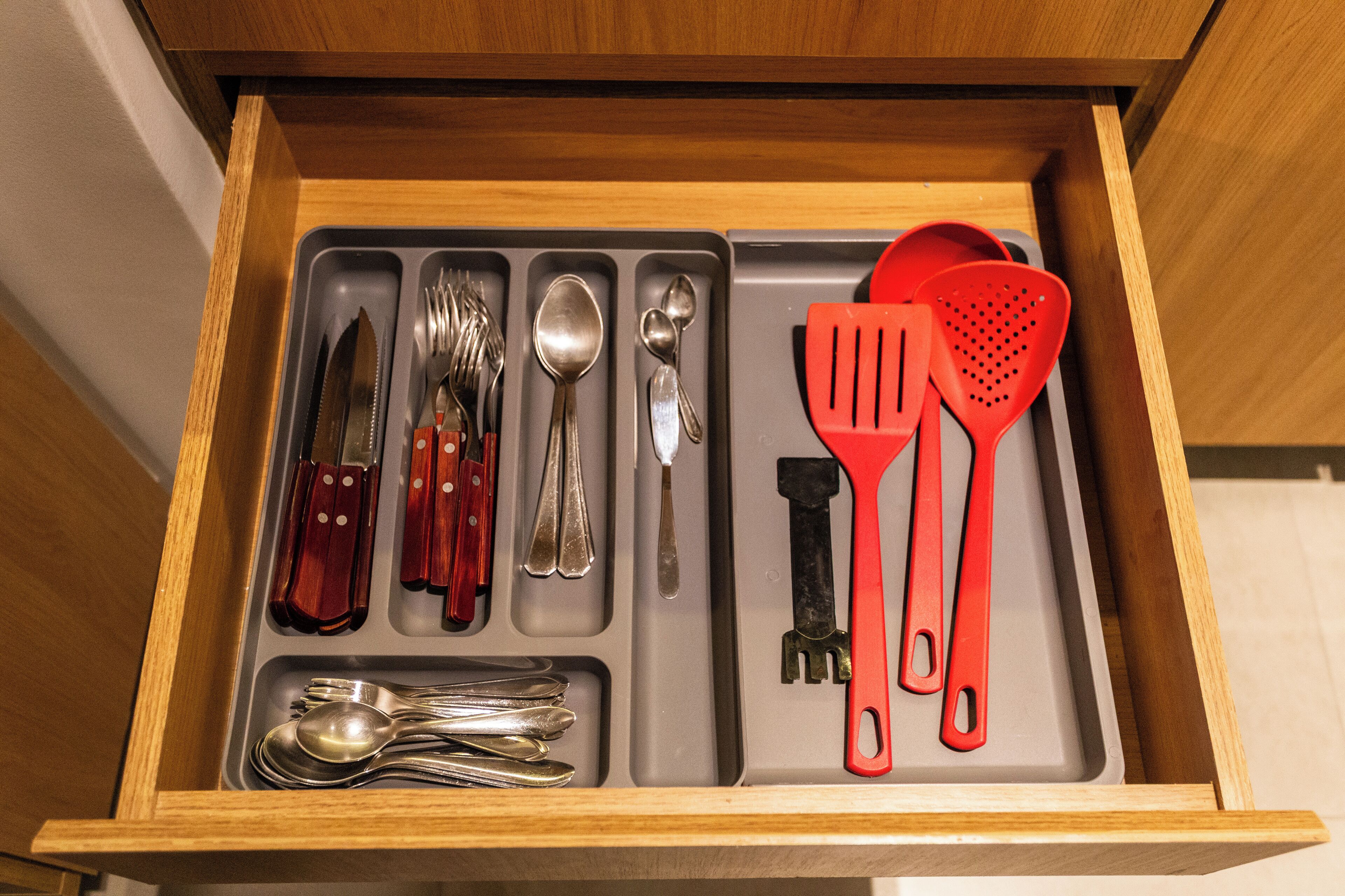 A drawer with compartments containing various kitchen utensils and cutlery.