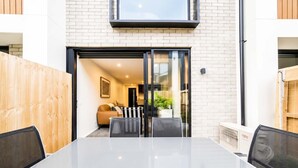 Et moderne interiør med en glasdør, der fører til en opholdsstue, et spisebord med stole, og en synlig klimaanlæg.