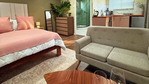 Ein Schlafzimmer mit Bett, Nachttisch und Beistelltisch. Es gibt einen Wohnbereich mit Sofa und Couchtisch.