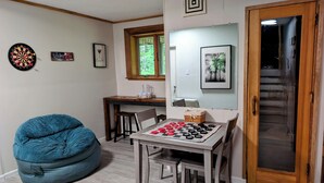 A room with a dining table, chairs, a bean bag, a dartboard, and a mirror. - Modern Mountain Escape – Fun Filled Retreat! (Bartlett)