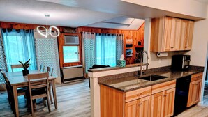 A modern kitchen with wooden cabinets, a granite countertop, and a built-in dishwasher. - Modern Mountain Escape – Fun Filled Retreat! (Bartlett)