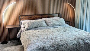 A bedroom with a wooden slat wall, a fluffy grey bedspread, and two bedside lamps. - Modern Mountain Escape – Fun Filled Retreat! (Bartlett)