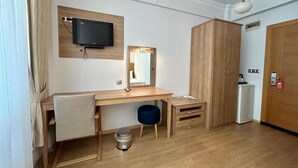 A hotel room with a wooden desk, a mirror, a television, a wardrobe, and a small kitchenette. - Casa Liva Otel Eskişehir (Eskişehir)