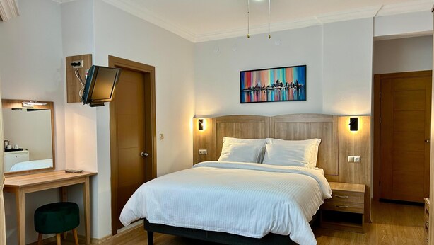 A hotel room with a bed, bedside tables, a desk, a chair, a mirror, a ceiling fan, and a painting on the wall. - Casa Liva Otel Eskişehir (Eskişehir)