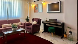 A modern living room with a sofa, armchair, coffee table, and a piano. - Casa Liva Otel Eskişehir (Eskişehir)
