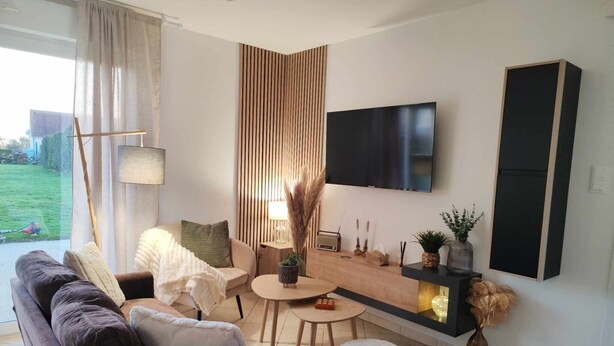A modern living room with a sofa, coffee table, and TV mounted on the wall.