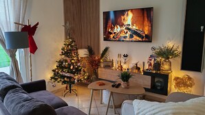 A cozy living room with a fireplace, a Christmas tree, and a television.