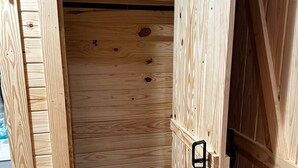 A wooden cabinet with a black latch, a wooden door, and a visible shelf inside. - Cozy cabin in Starkville (Starkville)