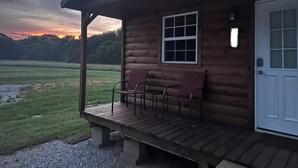 A log cabin with a porch, two chairs, a window, and a door. - Cozy cabin in Starkville (Starkville)