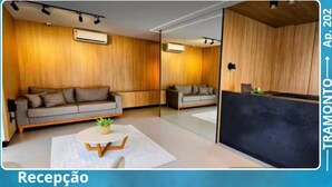 A modern reception area with a sofa, a small table, and a reception desk. - Cozy and modern apartment with balcony. (João Pessoa)