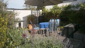 A patio with a table and chairs, surrounded by plants and a brick wall. - Apartment 'Mit Garten' with Private Terrace, Private Garden and Wi-Fi (Medebach)
