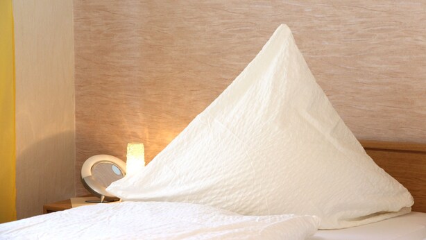 A bed with a white pillow and a bedside table with a lamp. - Apartment 'Mit Garten' with Private Terrace, Private Garden and Wi-Fi (Medebach)