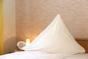 A bed with a white pillow and a bedside table with a lamp. - Apartment 'Ferienwohnung Hartmann' with private terrace, private garden and Wi-Fi (Medebach)