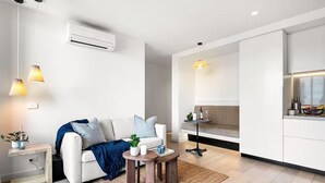 A modern living room with a sofa, coffee table, and pendant lights. - Cozy 1BR Melbourne Escape | Balcony | Pool | GYM (Melbourne)