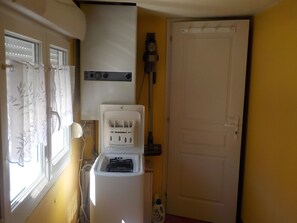 A compact room with a washing machine, a vacuum cleaner, and a door. - Holiday Home 'Gite618' (Helfaut)