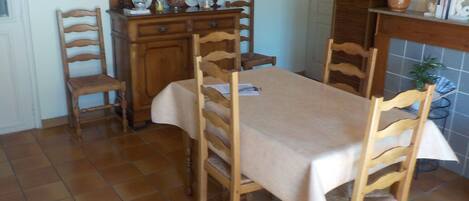 A dining area with a table set for four, surrounded by wooden chairs.