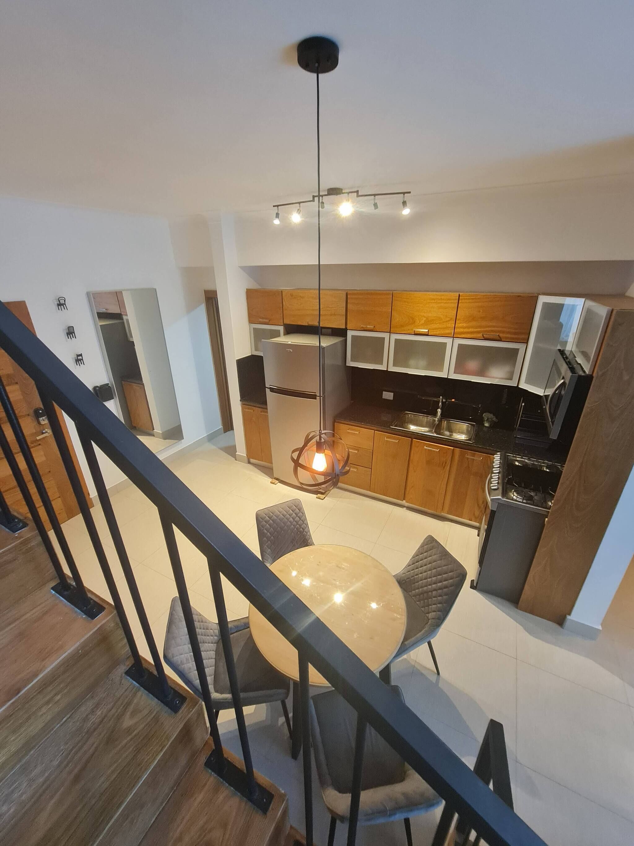 A modern kitchen with wooden cabinets, a built-in oven, and a dining area with a round table and chairs.