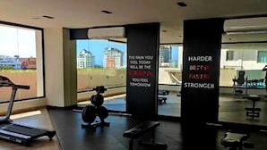 Ein Fitnessstudio mit Laufband, Gewichten und Bänken. An den Wänden befinden sich motivierende Sprüche.