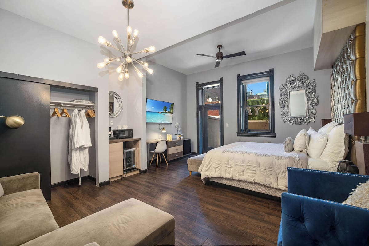 A bedroom with a bed, a desk, a chair, a wardrobe, and a ceiling fan.