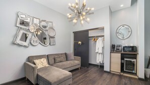 A modern living room with a grey sectional sofa, a wall-mounted mirror, and a unique light fixture. - Good Hotels Downtown Denver (Denver)