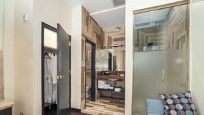 A hotel room with a wooden floor, a wardrobe with a mirror, a bed with a patterned pillow, and a small table with a lamp. - Good Hotels Downtown Denver (Denver)