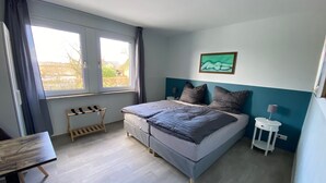 A bedroom with a bed, a small table, a chair, a bedside table with a lamp, and a window with curtains. - Renovated EFH, Schwerin lake district. Nature and culture within easy reach (Leezen)