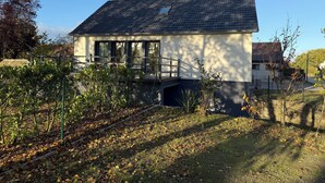 A single-story house with a dark roof, large windows, and a small balcony. - Renovated EFH, Schwerin lake district. Nature and culture within easy reach (Leezen)